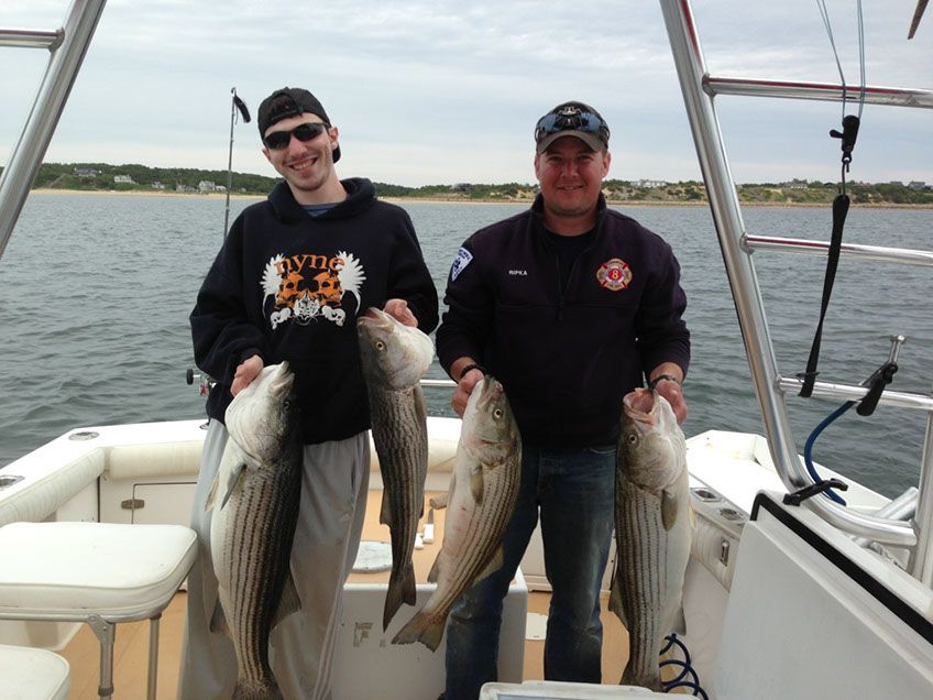 Two Men Holding Striper Fishes with Both Hands